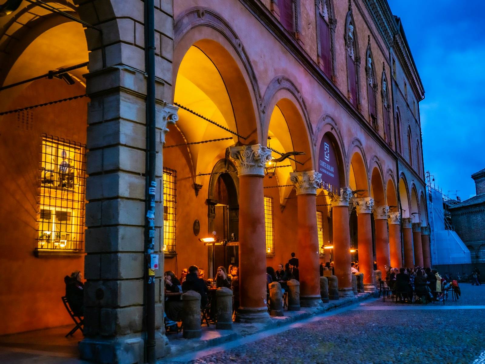People dining under lit porticoes in the evening